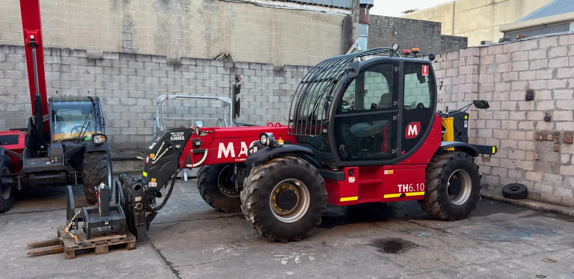 Magni TH6.10 six tonne telehandler with pallet fork attachments in a depot yard
